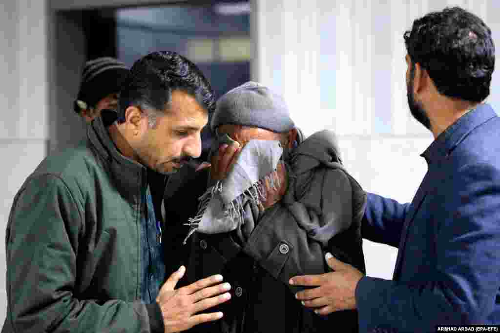 Several men comfort a relative of a victim... &nbsp;