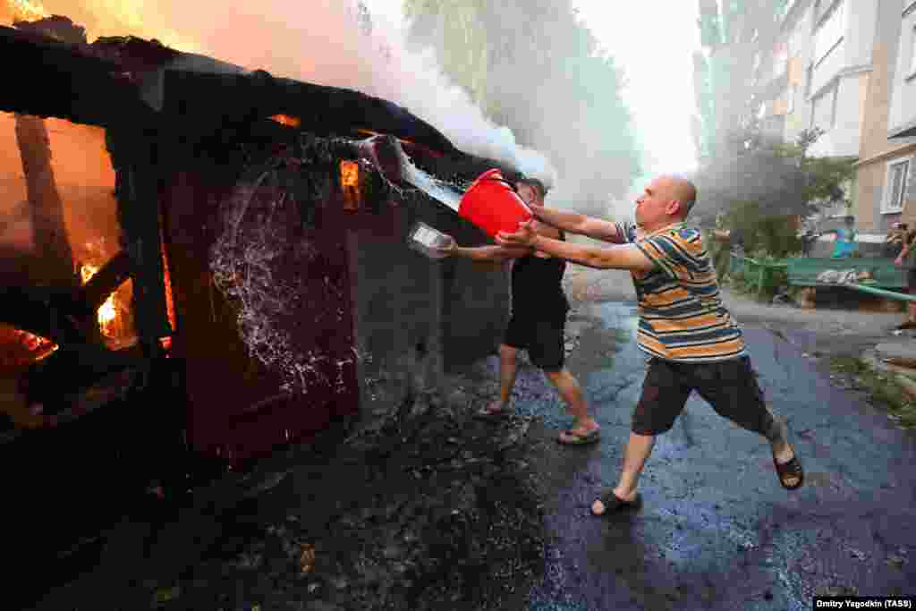 A man attempts to douse a fire with water after a strike on the Russian-held village of Lidiyevka in the Donetsk region on August 31. Kyiv has said it is advancing slowly to minimize losses. 