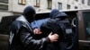 Ofițerii Agenției de Securitate Internă escortează un bărbat arestat sub suspiciunea de spionaj. Varșovia, Polonia (imagine de arhivă).