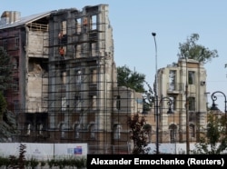 O echipă de construcții lucrează la ceea ce a mai rămas dintr-o clădire din Mariupol, ocupat de ruși, Ucraina, 16 august 2023.