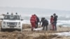 Rescue workers recover a body after a suspected migrant boat was shipwrecked off the coast of southern Italy. 