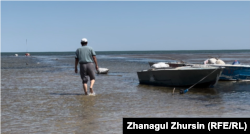 Fishermen must walk their boats nearly two kilometers to get past the shallow water.
