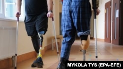 Ukrainian soldiers with prosthetic legs walk with crutches at a rehabilitation center near Lviv in western Ukraine.