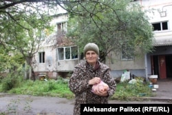 Olena Bubiyenko stands in front of the apartment building where she is now living in Ruski Tyshky, Kharkiv region, Ukraine.
