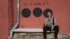 Hamlet Zinkivskiy sits in front of a mural he created in Kharkiv. The wording reads: "Yes! Or maybe no?"