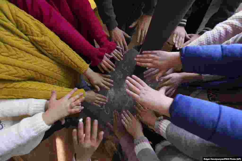 Schoolchildren warm themselves around a stove in their classroom in Stepanakert. 