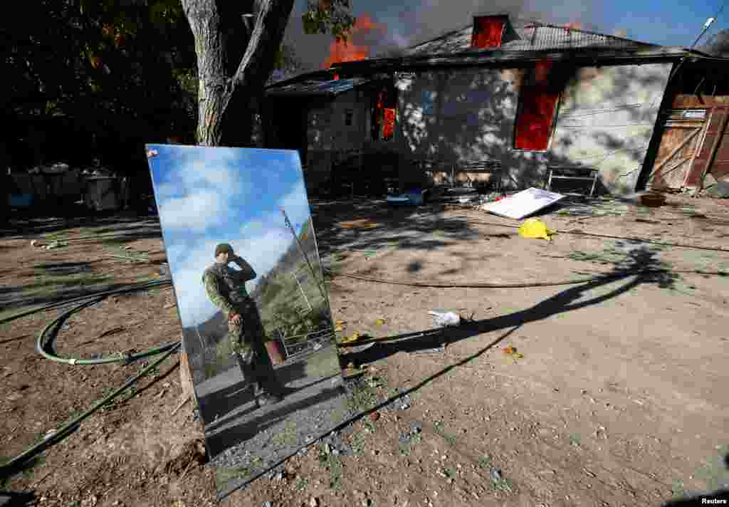 A man is reflected in a mirror near a house set on fire by departing ethnic Armenians in the village of Cherektar in Nagorno-Karabakh on November 14, 2020. Under the terms of the agreement, Armenians had to vacate certain parts of Nagorno-Karabakh. 