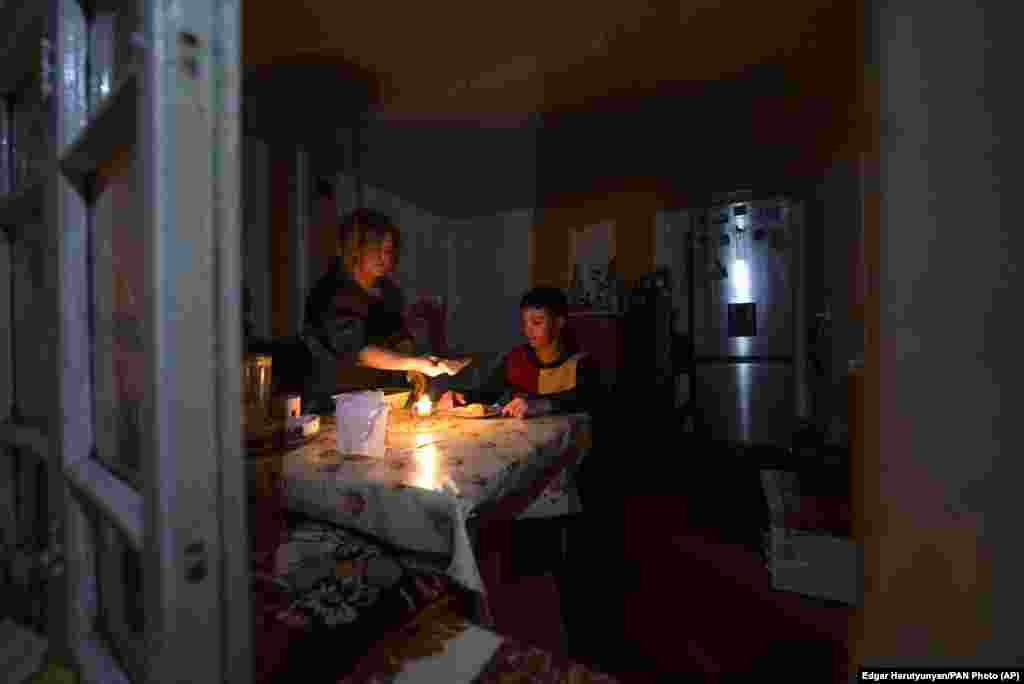 A woman and her son have dinner by candlelight at their home in Stepanakert. 