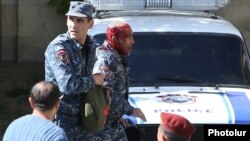 Armenia - A police officer helps a colleague injured during a clash with protesters in Yerevan, 16 April 2018.