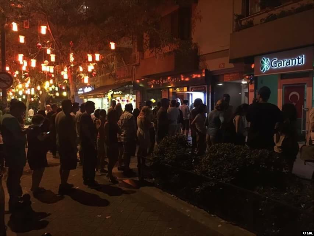 People queue to withdraw money from ATM machines.