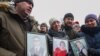 Каза болгондордун сүрөттөрүн кармап турган адамдар. 