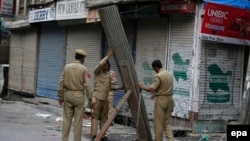 Indian police officers erect a tin and barbed wire barricade in Srinagar, the summer capital of Kashmir on July 11.