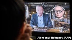 A woman watches an investigation by Aleksei Navalny into President Vladimir Putin's alleged "palace." The latest move by Russian authorities seems aimed at suppressing media coverage of such corruption exposés. 