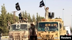 Militant Islamist fighters wave flags as they take part in a military parade in Syria's northern Raqqa province on June 30 to celebrate the announcement of a new Islamic Caliphate by ISIL. 