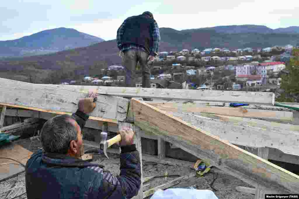 Residents repair a house damaged by shelling. Dozens of civilians on both sides of the conflict were killed during the hostilities, many in missile attacks. 