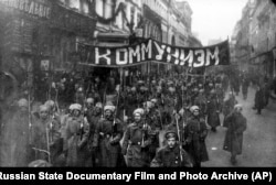 Armed soldiers carrying a banner reading "Communism" march along Nikolskaya Street toward the Kremlin in Moscow in 1917.