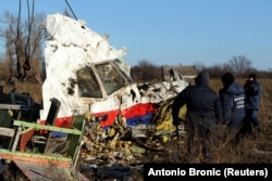 Muncitorii mută o bucată de epavă de la zborul Malaysia Airlines MH17 la locul prăbușirii avionului în apropiere de satul Hrabove, Ucraina, pe 20 noiembrie 2014.