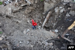 A child climbs out of a large shell crater in Pervomaisk in September.