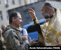 Священник благословляє російського полковника Ігоря Гіркіна (Стрєлкова), який на той час був одним із ватажків угруповання «ДНР», що визнане в Україні терористичним. Окупований Донецьк, 10 липня 2014 року