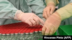 Laboratorijski tehničari rukuju zatvorenim bočicama kao dio testova punjenja i pakovanja vakcine protiv COVID-19 za veliku proizvodnju i opskrbu