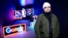 Chinese dissident artist Badiucao poses next to his neon lights artworks series on Hong Kong, in November 2021 at his exhibition in Brescia, Italy.