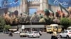 Vehicles travel past a huge banner in Tehran's Revolution Square as a cease-fire appeared to hold.